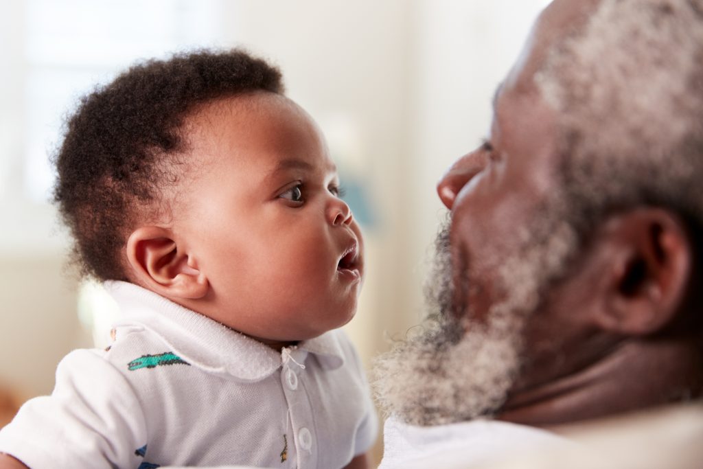 Proud Grandfather Cuddling Baby Grandson In Nursery At Home Proud Grandfather Cuddling Baby Grandson In Nursery At Home